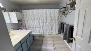Een badkamer met douchegordijn, toilet, wastafel en handdoekhouder.