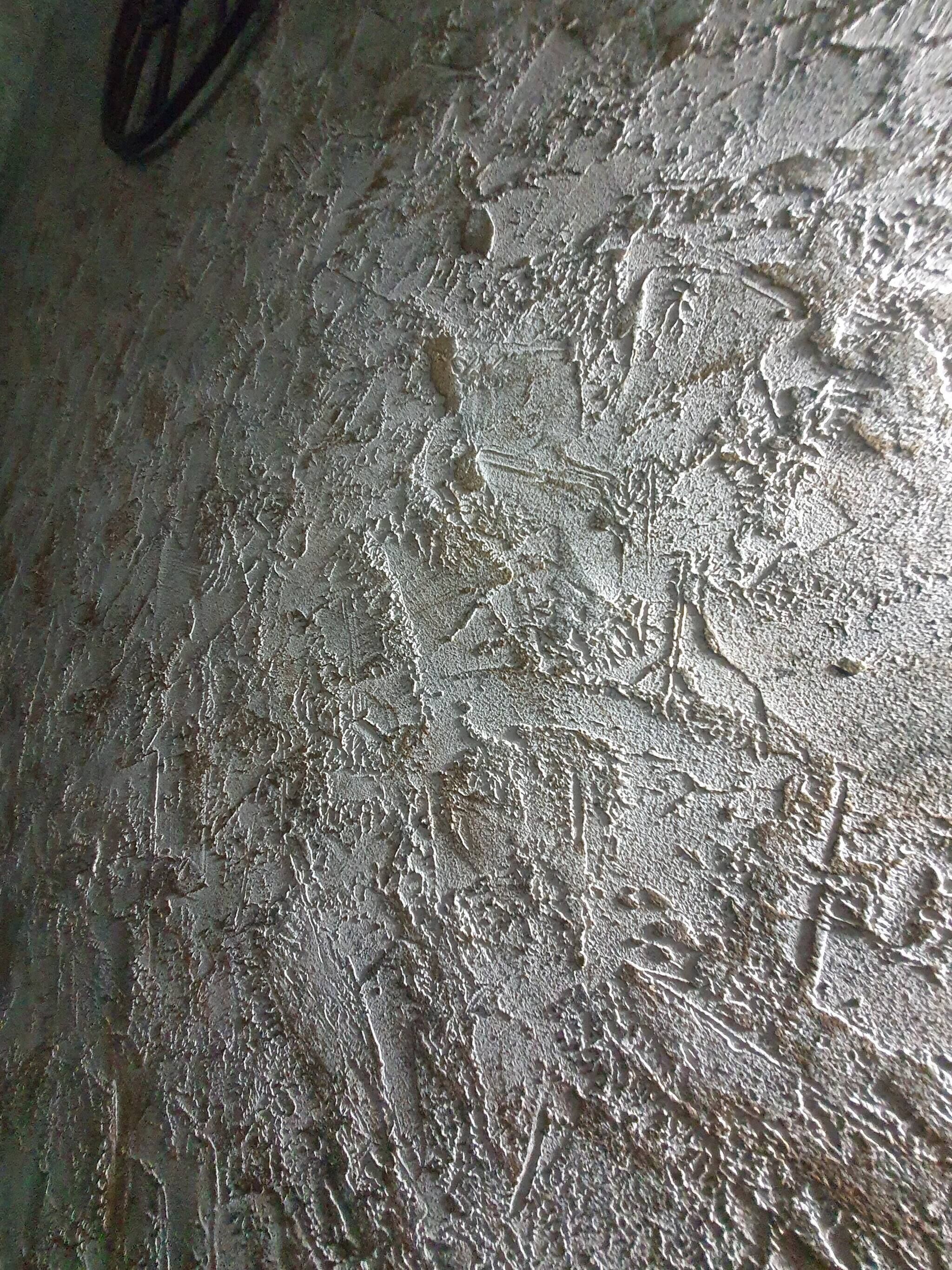 A textured wall with a rough surface, possibly indicating an older building or a specific architectural style.
