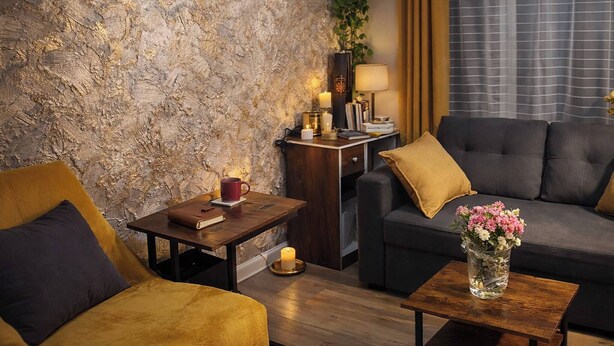 A cozy living room with a textured wall, a sofa, a coffee table with a vase, and a side table with a lamp and candles. - Luxury Smart Windsor London Parking (Slough)