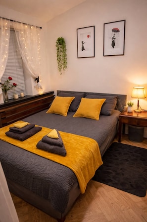 A neatly arranged bedroom with a bed, bedside table, lamp, and a small potted plant.