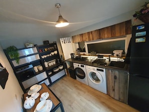 A compact kitchen with a washing machine, a stove, and a sink.