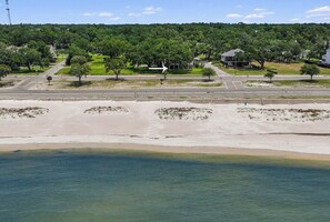 Eine Küstenstraße mit Strand, Bäumen und Häusern im Hintergrund.