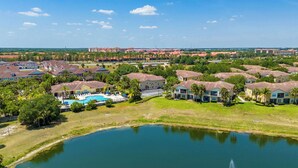 A residential area with houses, a swimming pool, and a body of water. - Blissful Disney Escape 2BR Minutes to Magic (Kissimmee)
