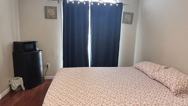 Une chambre à coucher avec un lit, une commode, un bureau et une fenêtre avec des rideaux.