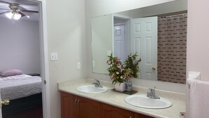 Une salle de bain avec deux lavabos, un miroir et un ventilateur de plafond.
