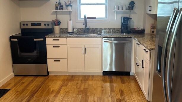 A modern kitchen with a stainless steel refrigerator, a built-in oven, a dishwasher, and wooden flooring. - MBC- Cozy home, Direct Access Snowmobile/ATV Trail (Presque Isle)