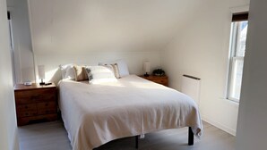 A bedroom with a bed, bedside tables, a lamp, a dresser, and a radiator. - MBC- Cozy home, Direct Access Snowmobile/ATV Trail (Presque Isle)