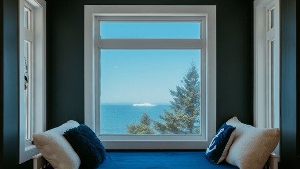 Ein Fensterplatz mit Blick auf das Meer und Bäume.