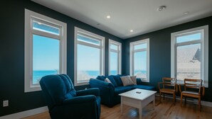 Ein Zimmer mit einem großen Fenster, einem blauen Sofa, einem weißen Couchtisch und zwei Holzsesseln.