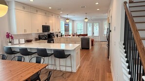 Una cocina amplia con una isla central, piso de madera y una escalera con barandilla de madera.