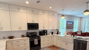 Una cocina moderna con armarios blancos, una estufa negra y un lavavajillas.