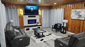 Una sala de estar con televisión, chimenea, sofás de cuero y alfombra de cuero de vaca.