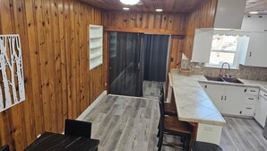 Una cocina con paredes de madera, una puerta negra, un fregadero y una ventana.