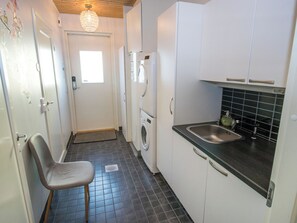 A compact kitchen with a washing machine, a sink, and a chair. - Nuorronranta by Interhome (Kangasala)