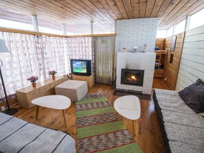 Een gezellige woonkamer met een open haard, een televisie en een comfortabele zithoek.