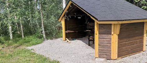 A wooden cabin with a hexagonal roof, a chimney, and a gravel ground.