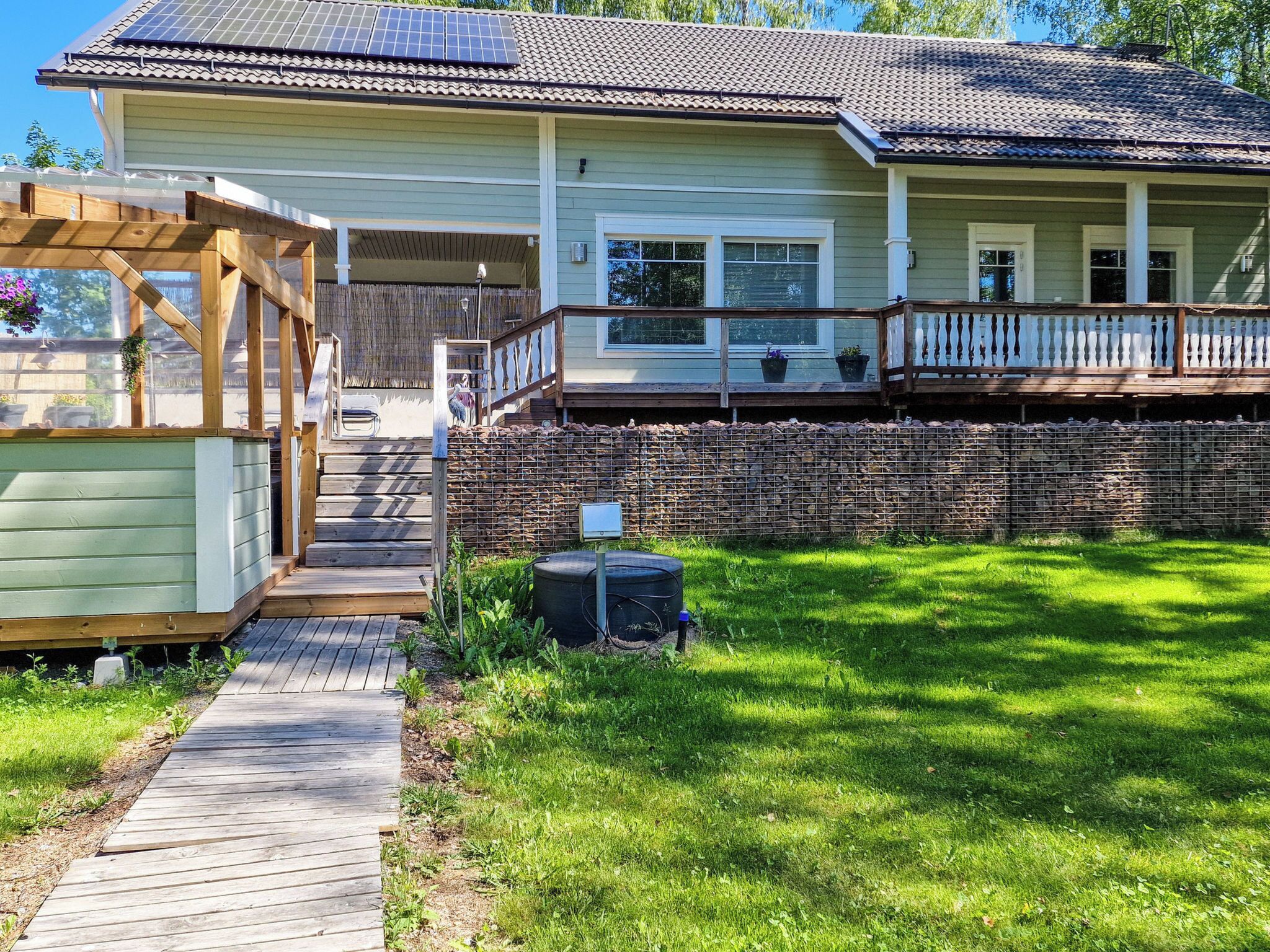 A two-story house with a covered porch, a fenced yard, and a solar panel array on the roof.