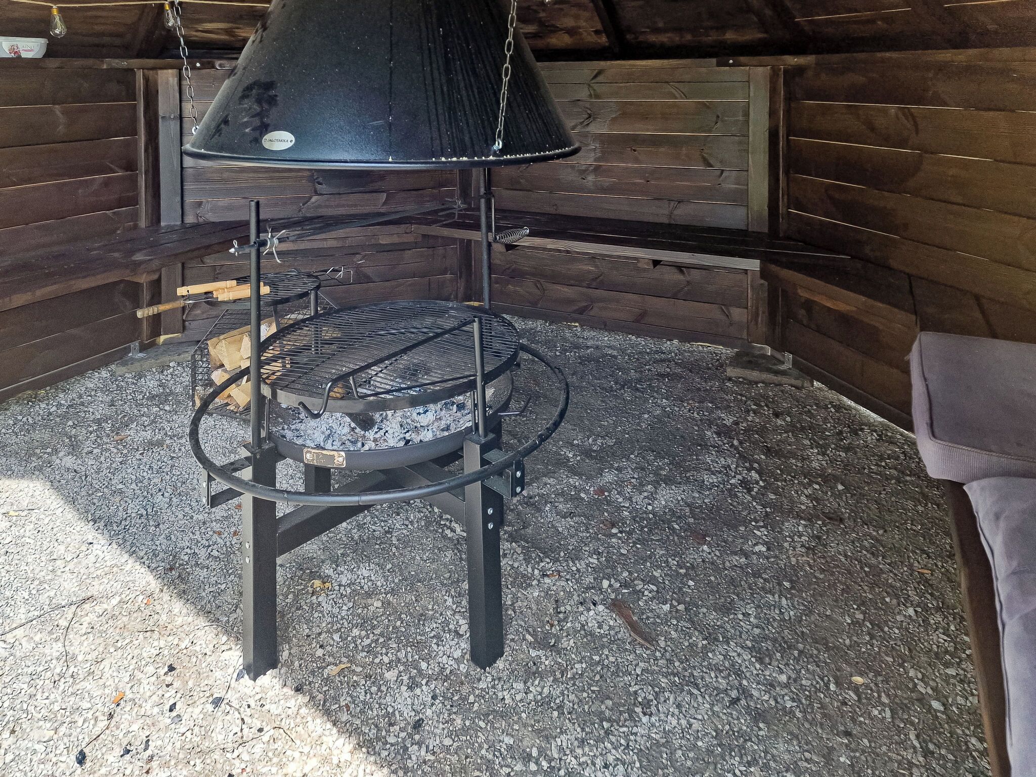 A wood-burning stove with a chimney, surrounded by a stone floor and wooden walls.