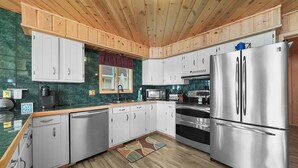 Eine moderne Küche mit Holzschränken, Edelstahlgeräten und einer grünen Spritzschutzwand.