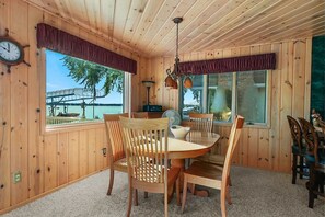 A wooden cabin with a dining area, a clock, and a view of a dock and water. - Waterfront Retreat w/ Dock on Lake Missaukee (Lake City)