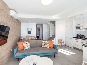 A modern living room with a sofa, a coffee table, and a kitchen area with white cabinets and appliances. - Apartment  by Interhome (Nerja)