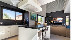 Een moderne keuken met een groot kookeiland, barstoelen en een televisie.