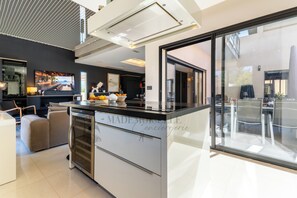 A modern kitchen with a built-in oven, a large window, and a television. - La Badoumba · Heated Pool & Jacuzzi (Saleilles)