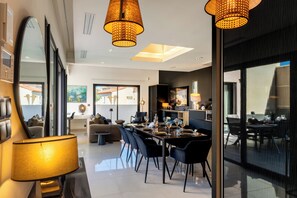 A modern dining area with a long table, black chairs, and a large mirror. - La Badoumba · Heated Pool & Jacuzzi (Saleilles)