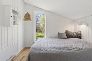 Ein Schlafzimmer mit einem großen Bett, einem Fenster und einer Pendelleuchte.