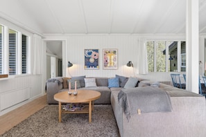 Ein Wohnzimmer mit einem grauen Sofa, einem runden Holztisch und zwei Wandleuchten.