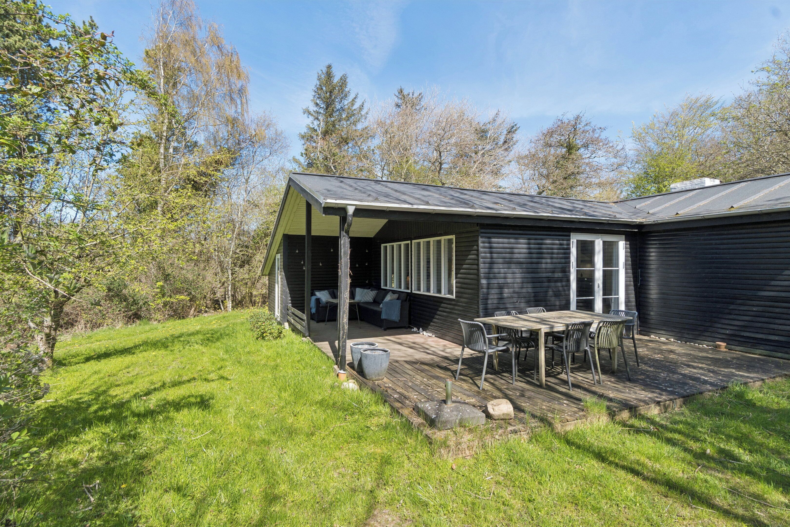 A house with a covered patio, a table and chairs, and a small garden area.