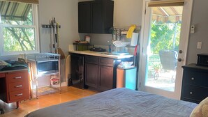 A bedroom with a large bed, a kitchenette with dark cabinets, a microwave, and a window. - Quaint 1-bedroom bed & breakfast with AC in Los Angeles (Los Angeles)