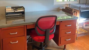 A room with a wooden desk, a red office chair, a flat-screen TV, a window with a view of trees, and a microwave. - Quaint 1-bedroom bed & breakfast with AC in Los Angeles (Los Angeles)