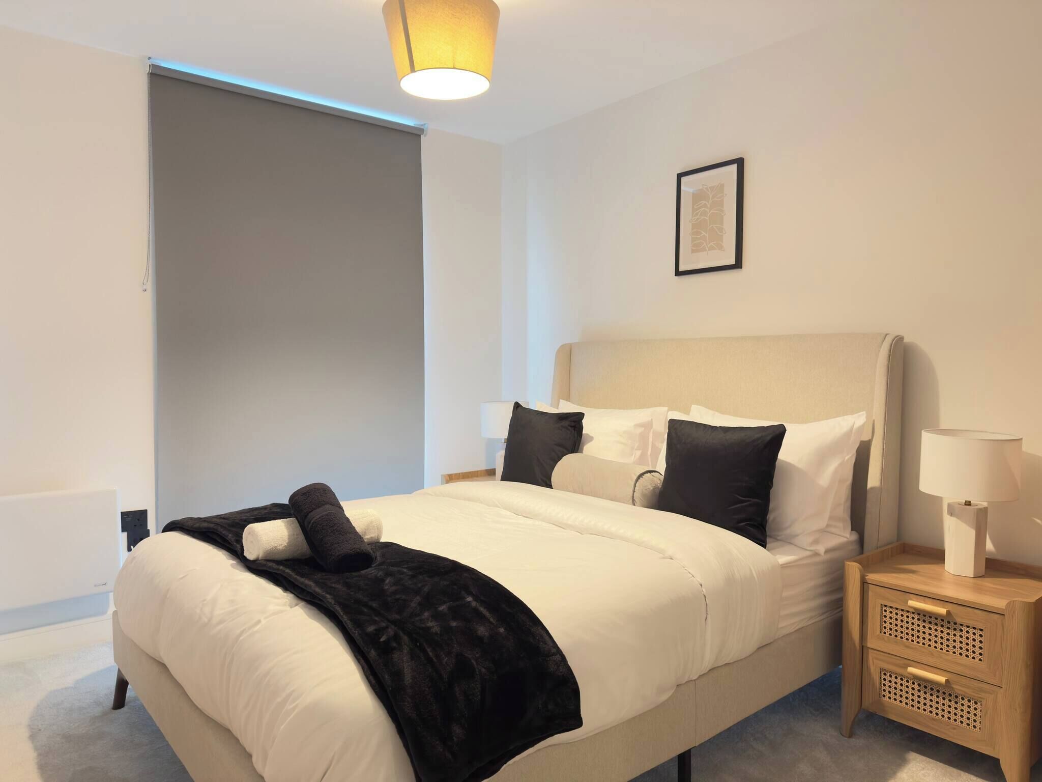 A hotel room with a bed, bedside tables, a lamp, and a framed picture on the wall.