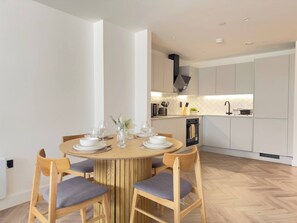 Eine moderne Küche mit weißen Schränken, einem Holztisch mit Stühlen und einem eingebauten Backofen.