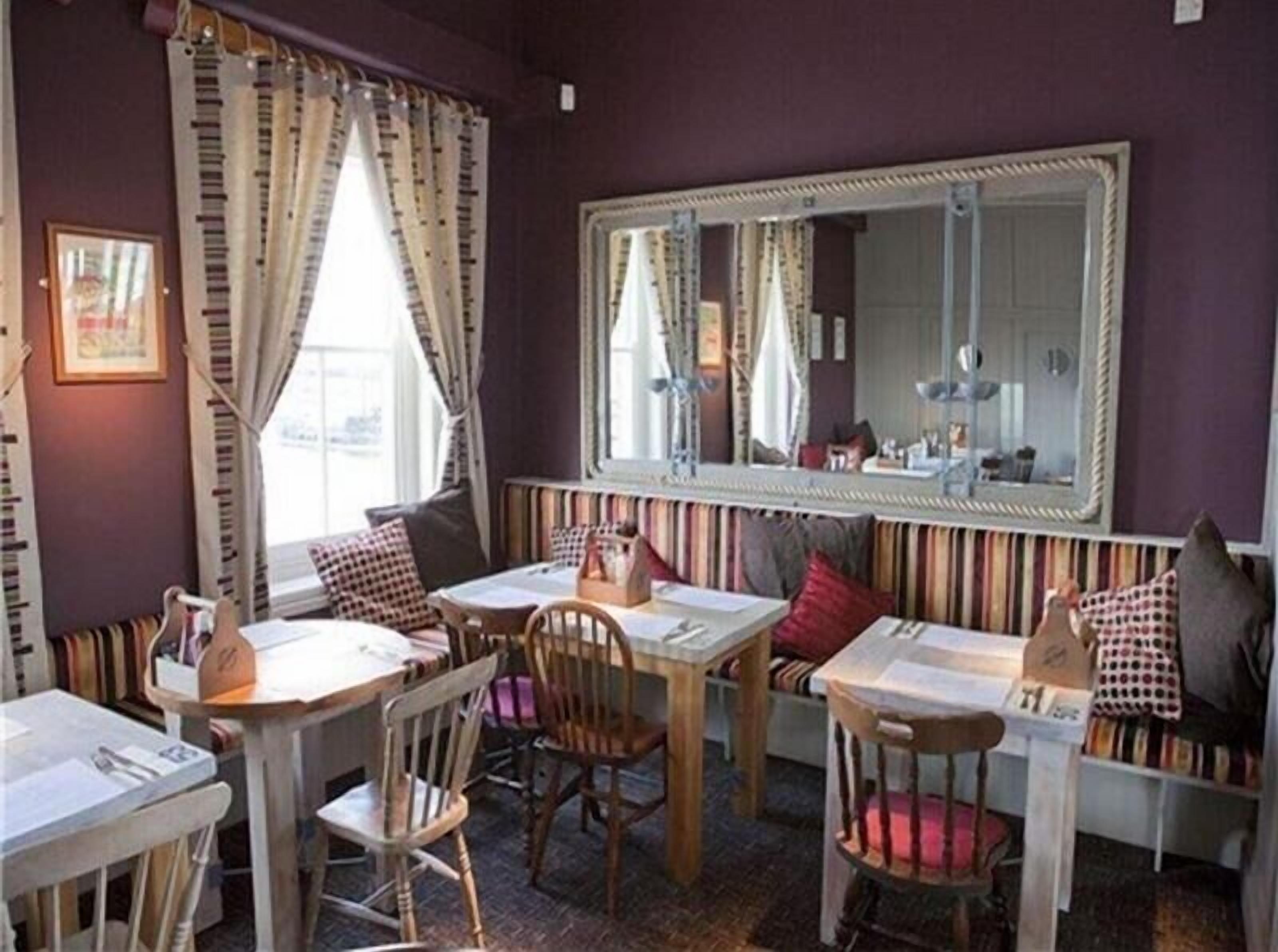 A room with a striped bench, a large mirror, and a window with curtains.