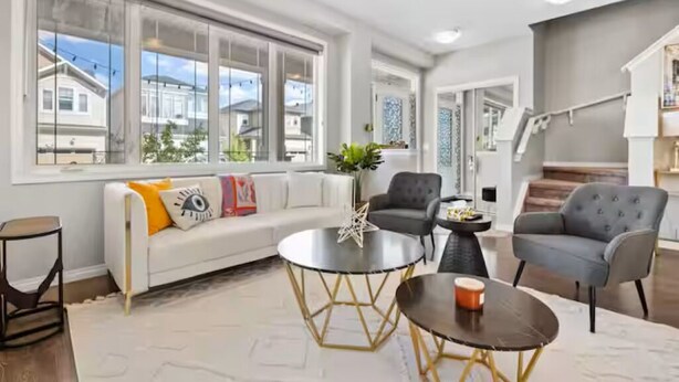 A spacious living room with a white sofa, two armchairs, a coffee table, and a large window offering a view of neighboring houses. - 5BR House » King Bed » AC » Pool Table » Garage (Calgary)