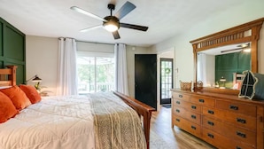 Un dormitorio con cama, cómoda, ventilador de techo y vistas al exterior.