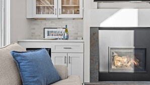 A modern kitchen with white cabinets, a built-in wine rack, and a fireplace.