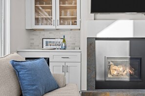 Eine moderne Küche mit weißen Schränken, einem integrierten Weinkühlschrank und einem Kamin.
