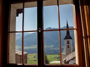 A window with a view of a church and mountains.