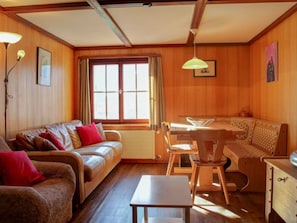 A cozy living room with a sofa, a dining table, and a chair.