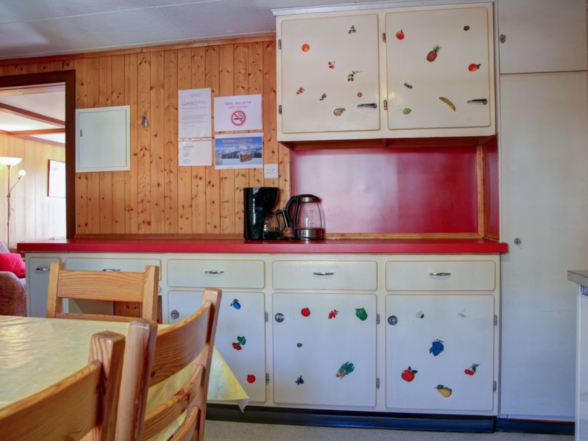 A kitchen with wooden cabinets, a coffee maker, and a dining table with chairs.