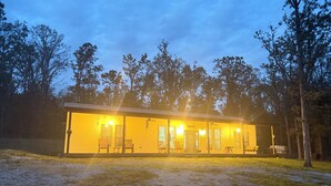 A yellow building with multiple windows and doors, surrounded by trees.