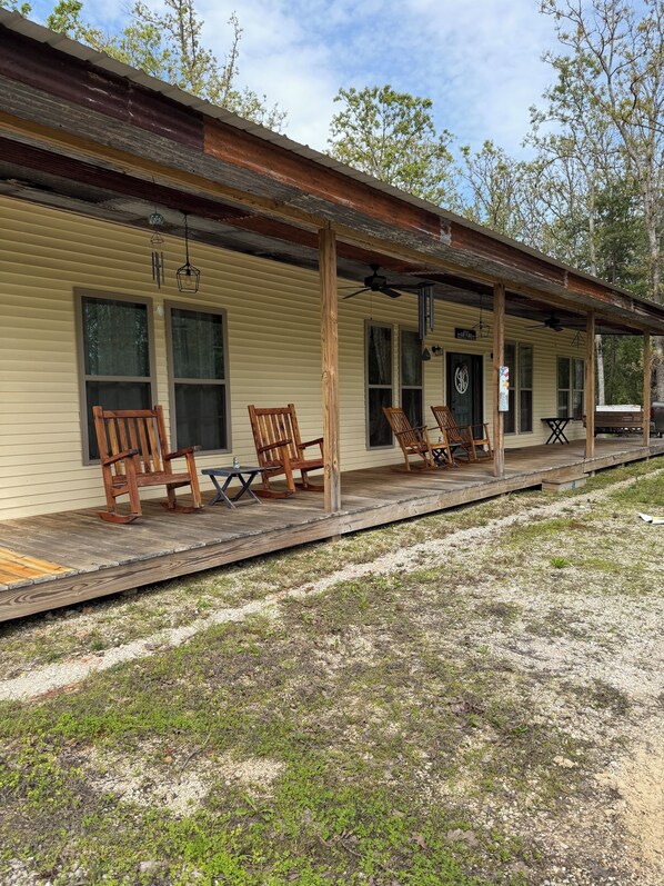 A rustic building with a porch, wooden rocking chairs, and a table. - Unique cabin in Salem Missouri, two bedroom two bath . Built in 2022. (Salem)