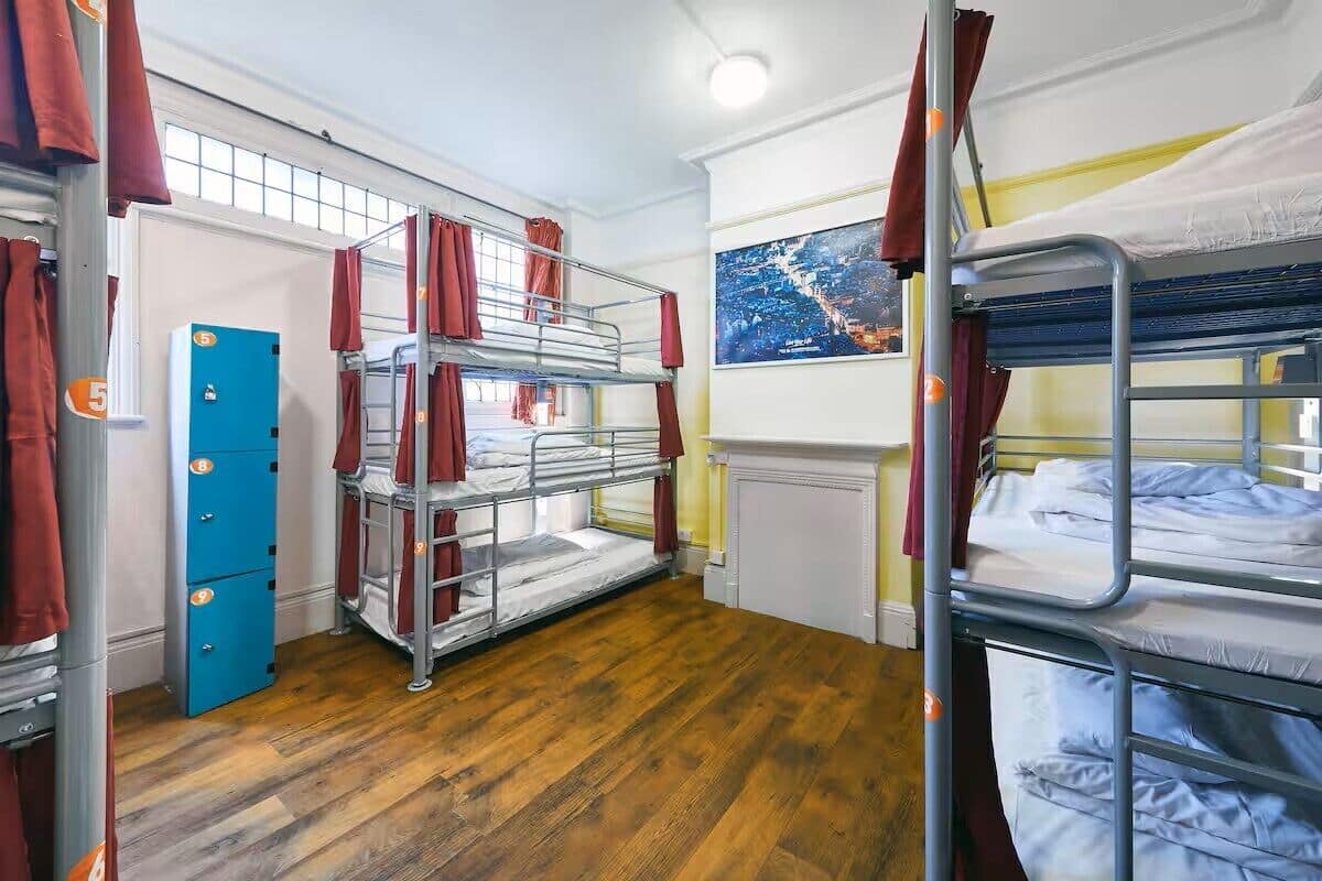 A dormitory room with bunk beds, a blue storage unit, and a map on the wall.