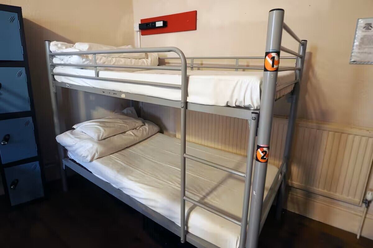 A bunk bed with two levels, a red emergency exit sign, and a blue storage unit with drawers.