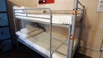 A bunk bed with two levels, a red emergency exit sign, and a blue storage unit with drawers.