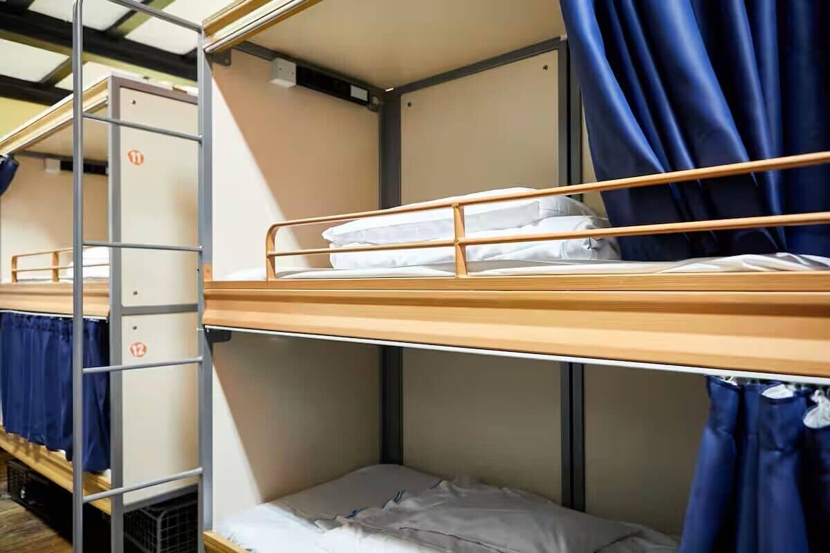 Bunk beds with metal railings, a ladder, and blue curtains.