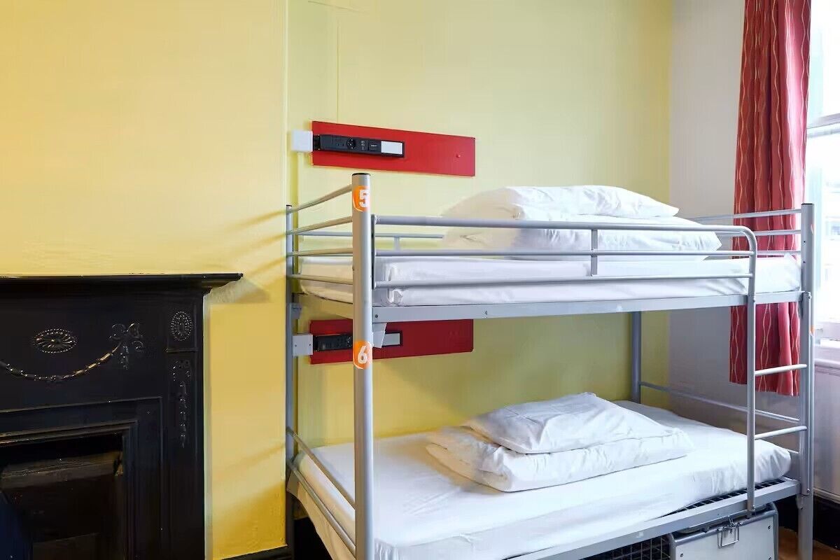 A bunk bed with a red headboard, a fireplace, and a red curtain.